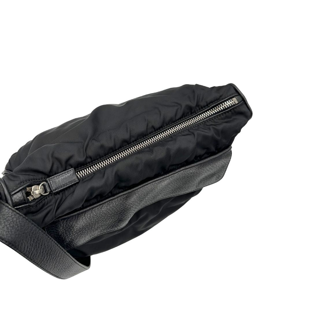 Chiusura di una Borsa Prada in nylon nero con parti metalliche argentate e dettagli in pelle tono su tono. Munita di una tracolla regolabile con fibbie, rifinita con logo triangolare sul lato destro. Originale, usata, di lusso, in condizioni buone.