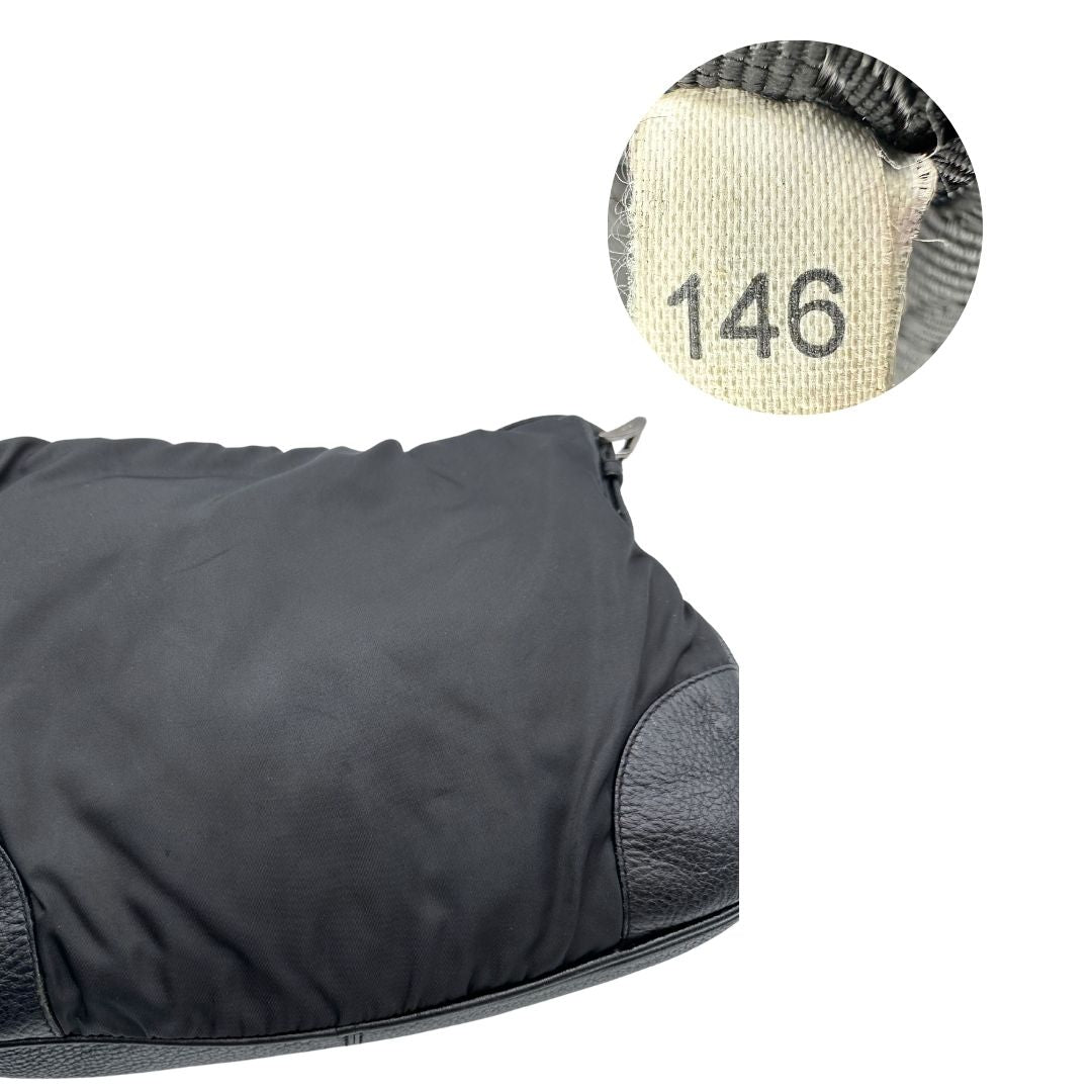 Borsa Prada in nylon nero con parti metalliche argentate e dettagli in pelle tono su tono. Munita di una tracolla regolabile con fibbie, rifinita con logo triangolare sul lato destro. Originale, usata, di lusso, in condizioni buone.