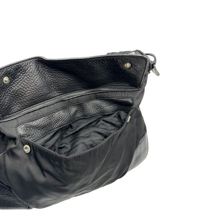 Tasca esterna di una Borsa Prada in nylon nero con parti metalliche argentate e dettagli in pelle tono su tono. Munita di una tracolla regolabile con fibbie, rifinita con logo triangolare sul lato destro. Originale, usata, di lusso, in condizioni buone.