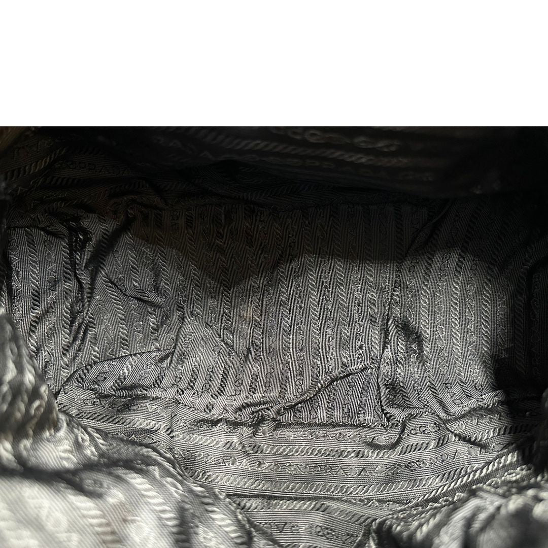 Interno di una Borsa Prada in nylon nero con parti metalliche argentate e dettagli in pelle tono su tono. Munita di una tracolla regolabile con fibbie, rifinita con logo triangolare sul lato destro. Originale, usata, di lusso, in condizioni buone.