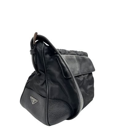 Lato destro di una Borsa Prada in nylon nero con parti metalliche argentate e dettagli in pelle tono su tono. Munita di una tracolla regolabile con fibbie, rifinita con logo triangolare sul lato destro. Originale, usata, di lusso, in condizioni buone.