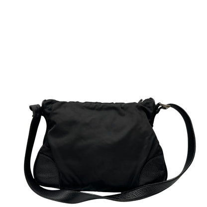 Lato sinistro di una Borsa Prada in nylon nero con parti metalliche argentate e dettagli in pelle tono su tono. Munita di una tracolla regolabile con fibbie, rifinita con logo triangolare sul lato destro. Originale, usata, di lusso, in condizioni buone.