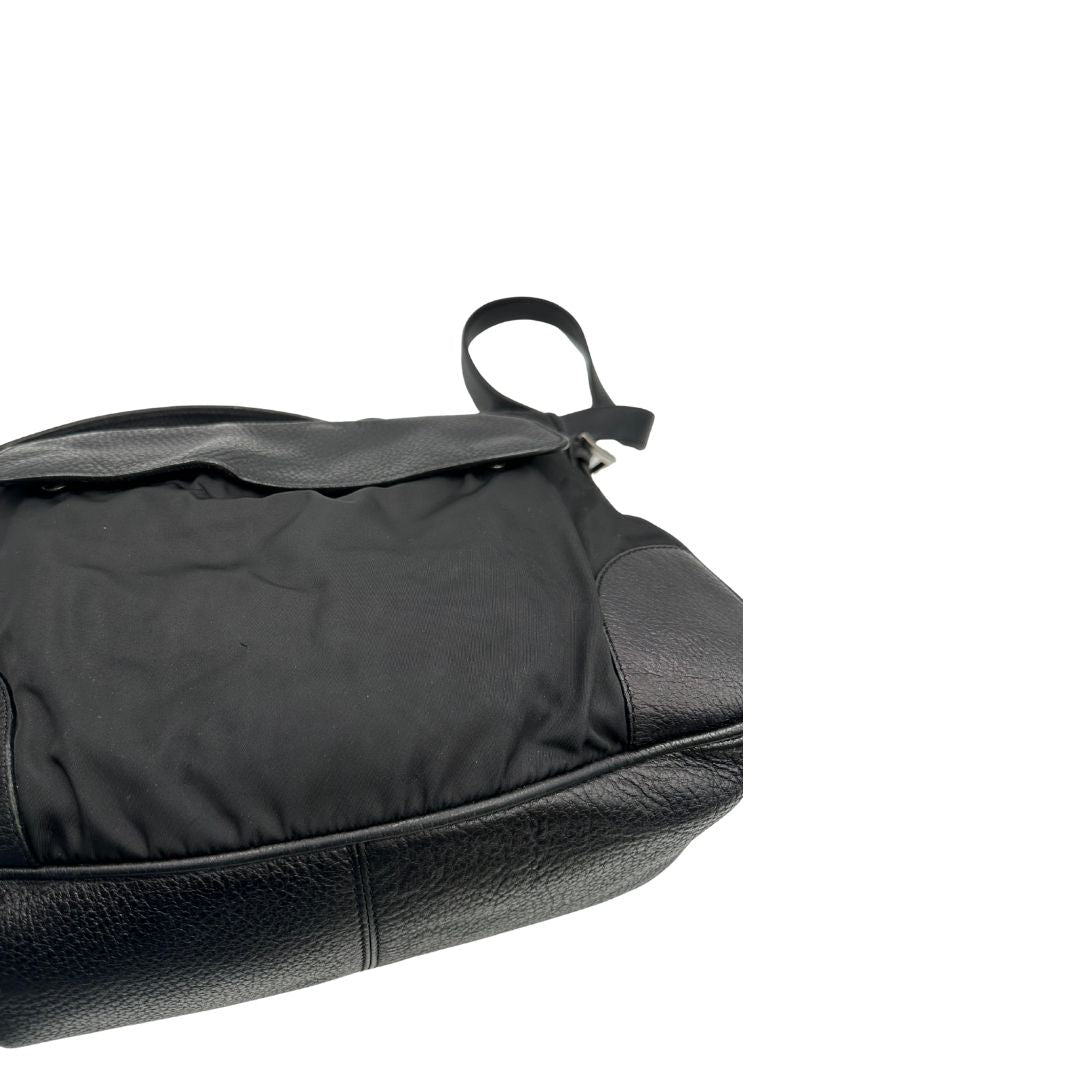 Borsa Prada in nylon nero con parti metalliche argentate e dettagli in pelle tono su tono. Munita di una tracolla regolabile con fibbie, rifinita con logo triangolare sul lato destro. Originale, usata, di lusso, in condizioni buone.