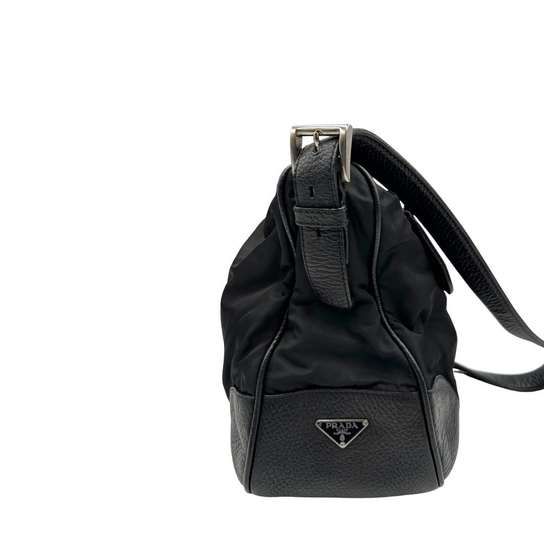 Borsa Prada in nylon nero con parti metalliche argentate e dettagli in pelle tono su tono. Munita di una tracolla regolabile con fibbie, rifinita con logo triangolare sul lato destro. Originale, usata, di lusso, in condizioni buone.