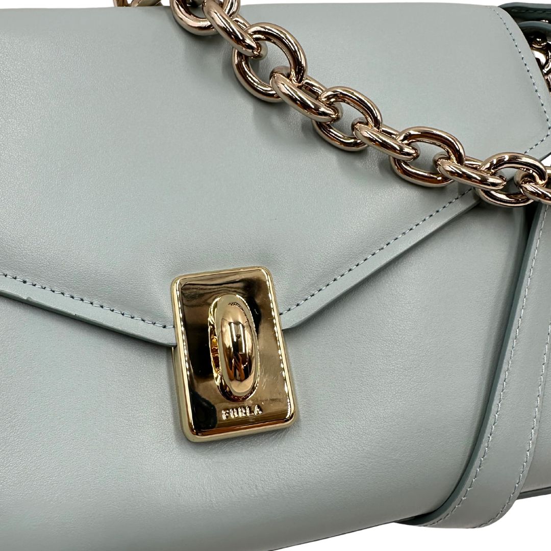 chiusura Borsa Furla in pelle celeste con parti metalliche dorate; munita di un manico in catena e una tracolla regolabile. Completa di dustbag, di lusso, usata. 