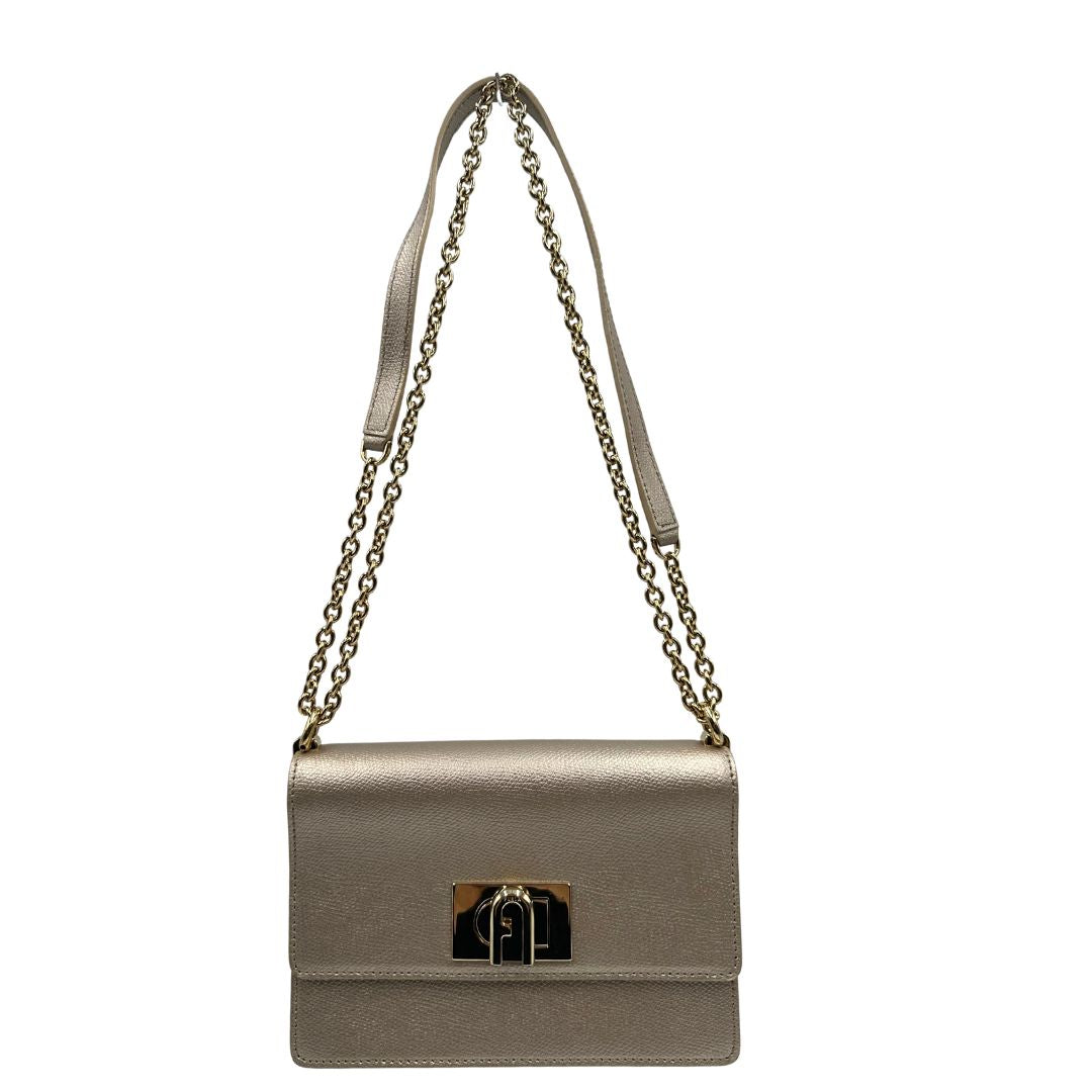 Front di una Pochette Furla in pelle martellata color champagne con parti metalliche dorate, munita di una tracolla in catena scorrevole con spallaccio in pelle. Completa di dustbag. Originale, usata, di lusso, in ottime condizioni