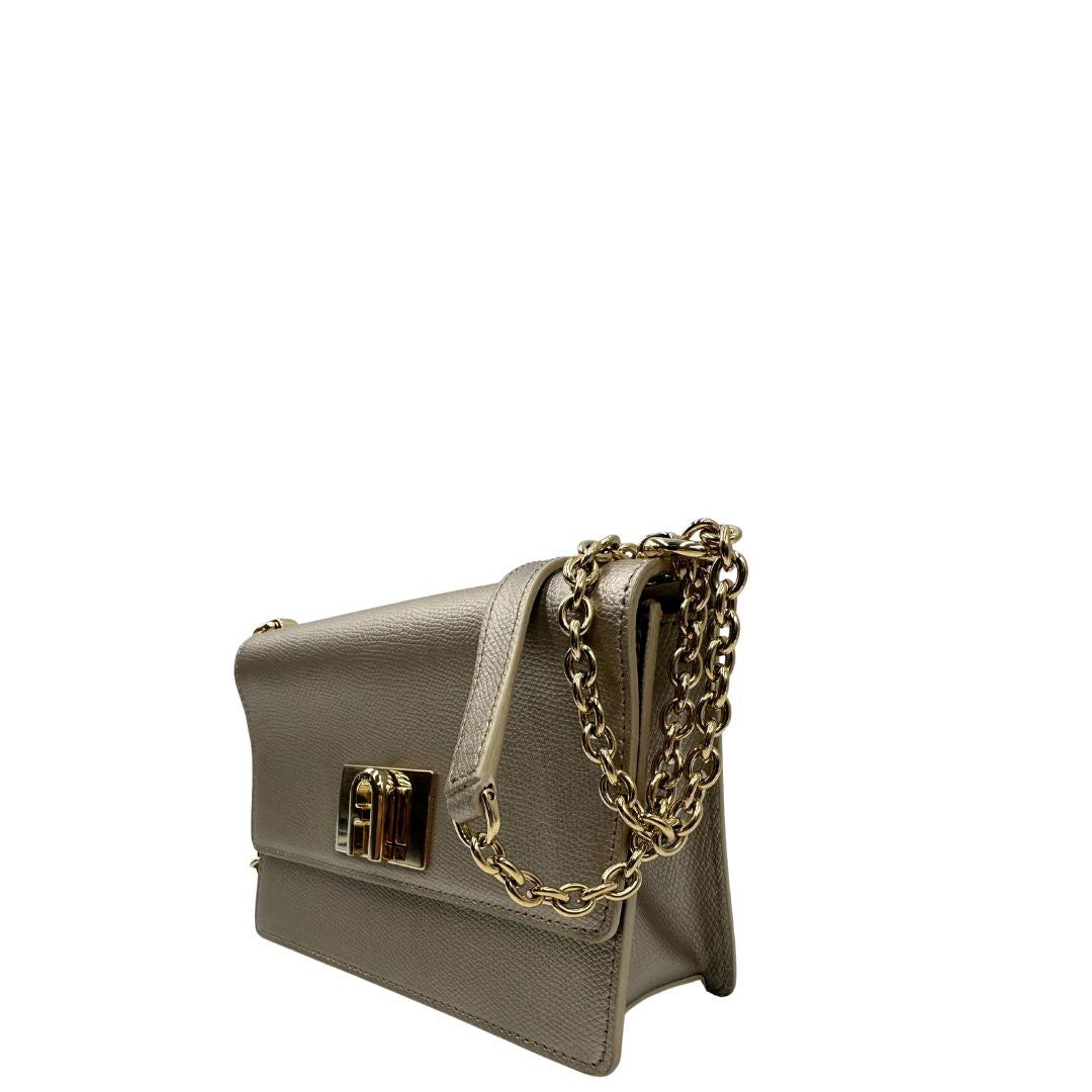 Lato sinistro di una Pochette Furla in pelle martellata color champagne con parti metalliche dorate, munita di una tracolla in catena scorrevole con spallaccio in pelle. Completa di dustbag. Originale, usata, di lusso, in ottime condizioni