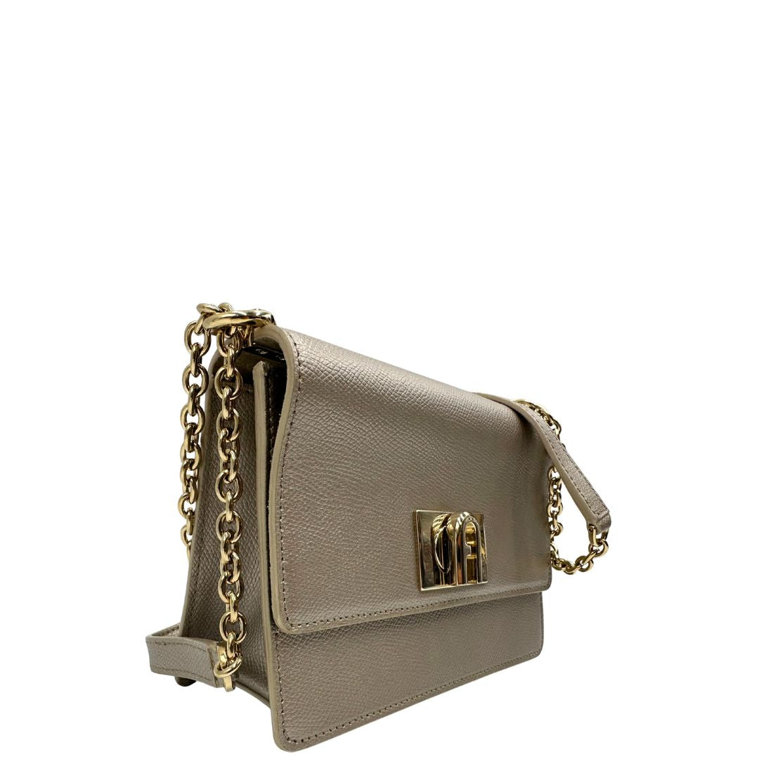 Lato destro di una Pochette Furla in pelle martellata color champagne con parti metalliche dorate, munita di una tracolla in catena scorrevole con spallaccio in pelle. Completa di dustbag. Originale, usata, di lusso, in ottime condizioni