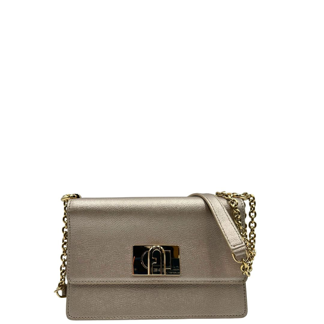 Front di una Pochette Furla in pelle martellata color champagne con parti metalliche dorate, munita di una tracolla in catena scorrevole con spallaccio in pelle. Completa di dustbag. Originale, usata, di lusso, in ottime condizioni