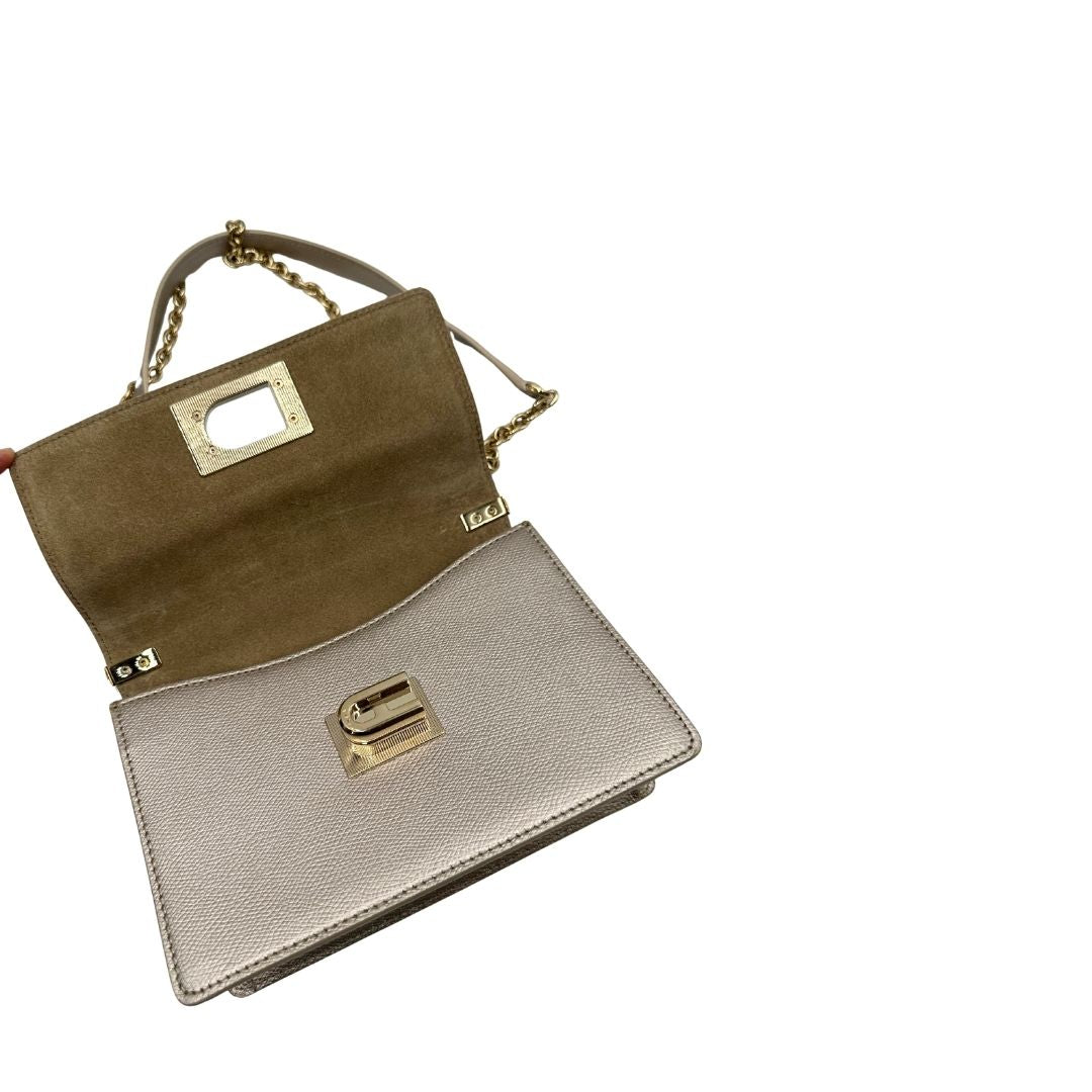 Interno di una Pochette Furla in pelle martellata color champagne con parti metalliche dorate, munita di una tracolla in catena scorrevole con spallaccio in pelle. Completa di dustbag. Originale, usata, di lusso, in ottime condizioni