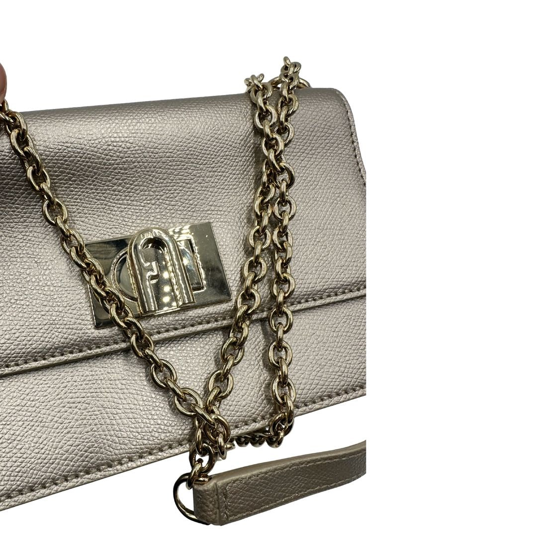 Pochette Furla in pelle martellata color champagne con parti metalliche dorate, munita di una tracolla in catena scorrevole con spallaccio in pelle. Completa di dustbag. Originale, usata, di lusso, in ottime condizioni