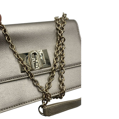 Pochette Furla in pelle martellata color champagne con parti metalliche dorate, munita di una tracolla in catena scorrevole con spallaccio in pelle. Completa di dustbag. Originale, usata, di lusso, in ottime condizioni