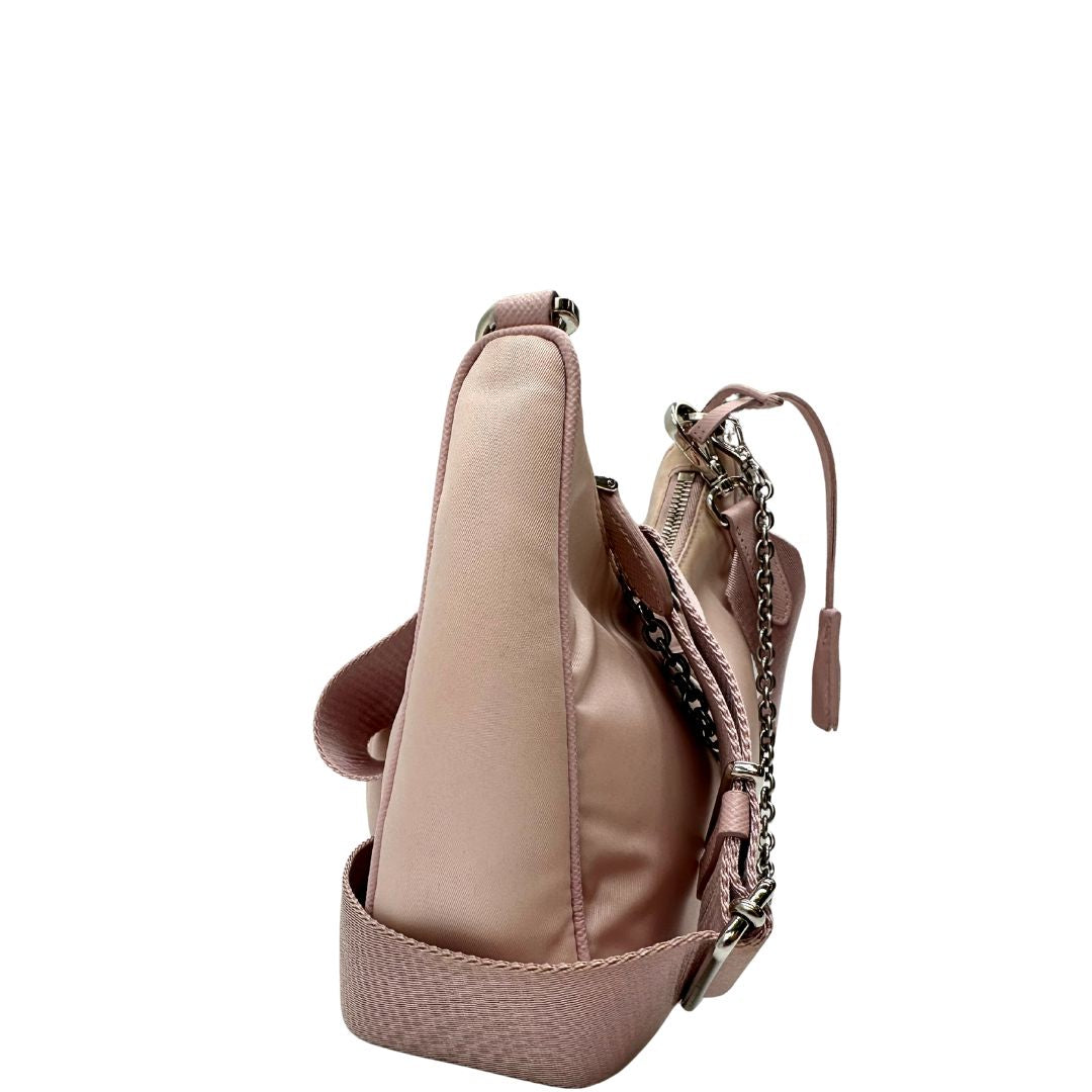 lato Borsa Prada in nylon rosa con parti metalliche argentate e finiture in pelle tono su tono; munita di un mini pouch amovibile, un accessorio portachiavi, manico in catena e una tracolla in tessuto amovibile e regolabile, di lusso, originale, ottime condizioni. 