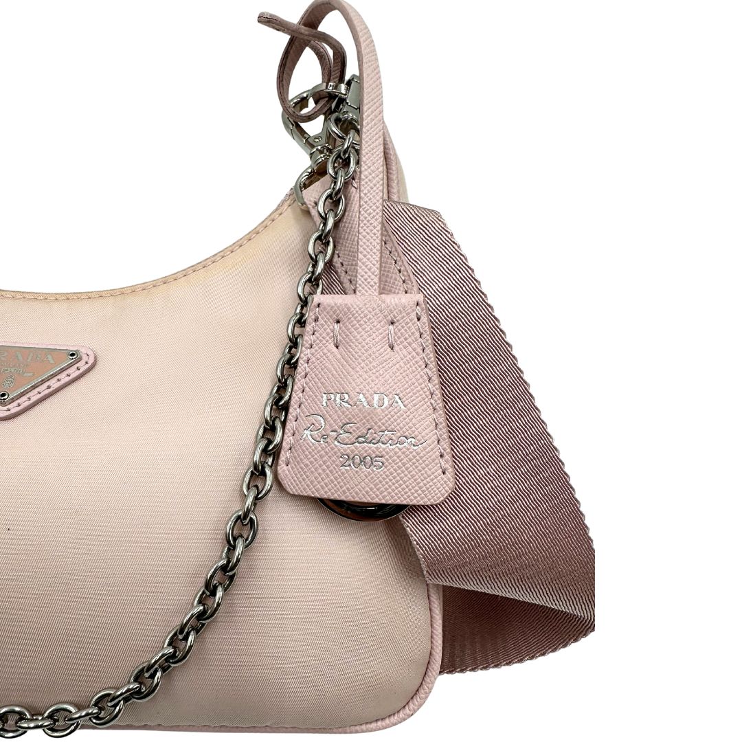 lato Borsa Prada in nylon rosa con parti metalliche argentate e finiture in pelle tono su tono; munita di un mini pouch amovibile, un accessorio portachiavi, manico in catena e una tracolla in tessuto amovibile e regolabile, di lusso, originale, ottime condizioni. 