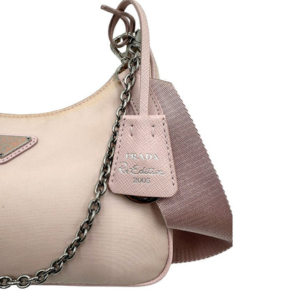 lato Borsa Prada in nylon rosa con parti metalliche argentate e finiture in pelle tono su tono; munita di un mini pouch amovibile, un accessorio portachiavi, manico in catena e una tracolla in tessuto amovibile e regolabile, di lusso, originale, ottime condizioni. 