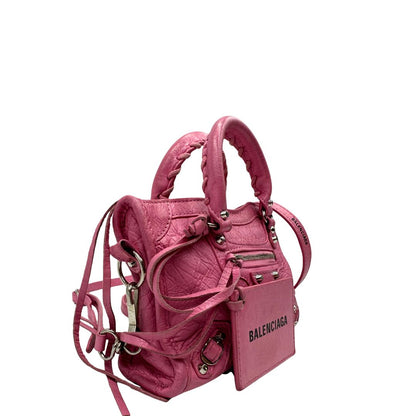 Lato destro di una Borsa Neo Cagole Balenciaga City in pelle crinkled rosa bubblegum. Dotata di doppi manici con dettaglio intreccio e tracolla regolabile e amovibile, completa del classico specchietto. Rifinita con borchie in metallo argentato. Originale, usata, di lusso, in ottime condizioni