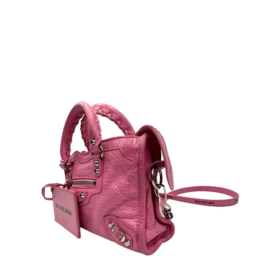 Lato sinistro di una Borsa Neo Cagole Balenciaga City in pelle crinkled rosa bubblegum. Dotata di doppi manici con dettaglio intreccio e tracolla regolabile e amovibile, completa del classico specchietto. Rifinita con borchie in metallo argentato. Originale, usata, di lusso, in ottime condizioni