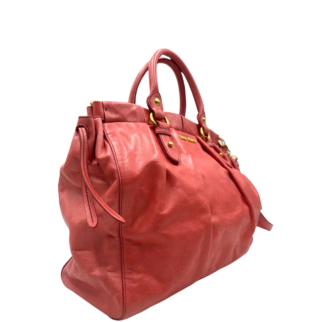 lato Borsa Miu Miu in pelle color rosa corallo con parti metalliche dorate; munita di doppi manici stondati e una tracolla amovibile. Completa di dustbag, di lusso, originale, ottime condizioni. 