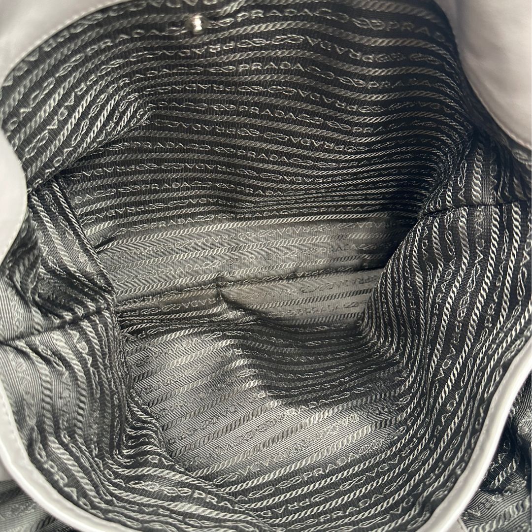 interno Borsa Prada in pelle grigia con parti metalliche argentate; impreziosita da zip laterali e accessorio porta address, munita di doppi manici stondati e una tracolla amovibile e regolabile. Completa di dustbag, di lusso, originale, ottime condizioni.
