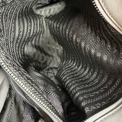 interno Borsa Prada in pelle grigia con parti metalliche argentate; impreziosita da zip laterali e accessorio porta address, munita di doppi manici stondati e una tracolla amovibile e regolabile. Completa di dustbag, di lusso, originale, ottime condizioni.