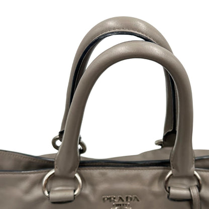 manici Borsa Prada in pelle grigia con parti metalliche argentate; impreziosita da zip laterali e accessorio porta address, munita di doppi manici stondati e una tracolla amovibile e regolabile. Completa di dustbag, di lusso, originale, ottime condizioni.