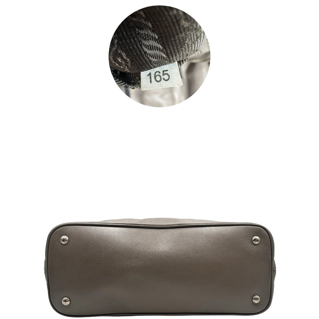 base Borsa Prada in pelle grigia con parti metalliche argentate; impreziosita da zip laterali e accessorio porta address, munita di doppi manici stondati e una tracolla amovibile e regolabile. Completa di dustbag, di lusso, originale, ottime condizioni.