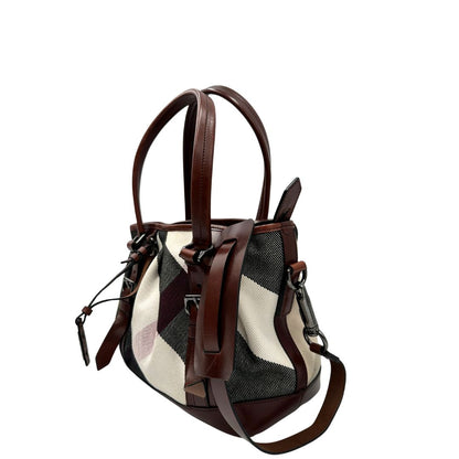 Lato sinistro di una Borsa Tote Burberry in tessuto bianco trama tartan nera e rossa, finiture in pelle marrone e parti metalliche effetto renio, munita di doppie manici e una tracolla regolabile, amovibile con spallaccio. Indossabile a spalla. Originale, usata, di lusso, in ottime condizioni.