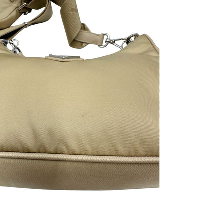 Borsa Prada in Re-Nylon beige con finiture in pelle saffiano tono su tono, munita di un manico in catena e una tracolla in tessuto regolabile e amovibile, impreziosita da pouch rimovibile. Rifinita con parti metalliche argentate e iconico triangolo logato sul front. Indossabile a spalla oppure a tracolla. Originale, usata, di lusso, in ottime condizioni