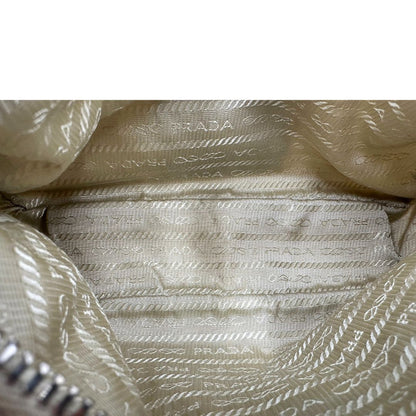 Inerno di una Borsa Prada in Re-Nylon beige con finiture in pelle saffiano tono su tono, munita di un manico in catena e una tracolla in tessuto regolabile e amovibile, impreziosita da pouch rimovibile. Rifinita con parti metalliche argentate e iconico triangolo logato sul front. Indossabile a spalla oppure a tracolla. Originale, usata, di lusso, in ottime condizioni