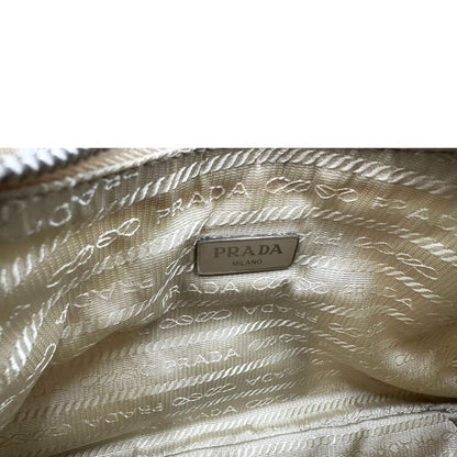 Interno di una Borsa Prada in Re-Nylon beige con finiture in pelle saffiano tono su tono, munita di un manico in catena e una tracolla in tessuto regolabile e amovibile, impreziosita da pouch rimovibile. Rifinita con parti metalliche argentate e iconico triangolo logato sul front. Indossabile a spalla oppure a tracolla. Originale, usata, di lusso, in ottime condizioni