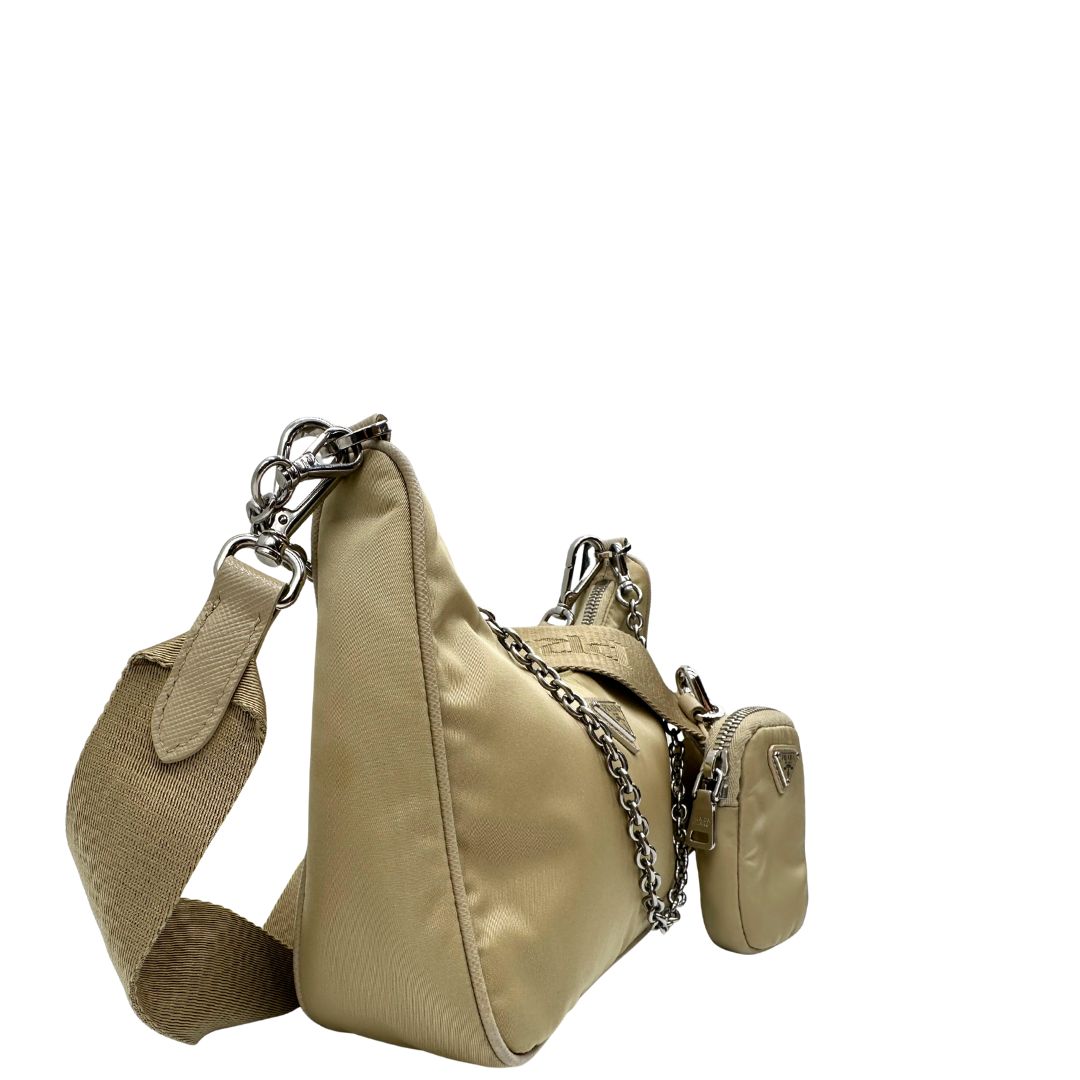 Lato destro di una Borsa Prada in Re-Nylon beige con finiture in pelle saffiano tono su tono, munita di un manico in catena e una tracolla in tessuto regolabile e amovibile, impreziosita da pouch rimovibile. Rifinita con parti metalliche argentate e iconico triangolo logato sul front. Indossabile a spalla oppure a tracolla. Originale, usata, di lusso, in ottime condizioni