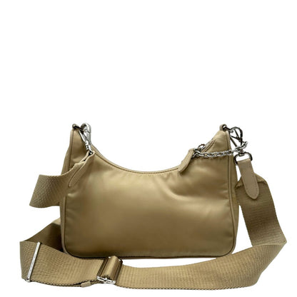 Retro di una Borsa Prada in Re-Nylon beige con finiture in pelle saffiano tono su tono, munita di un manico in catena e una tracolla in tessuto regolabile e amovibile, impreziosita da pouch rimovibile. Rifinita con parti metalliche argentate e iconico triangolo logato sul front. Indossabile a spalla oppure a tracolla. Originale, usata, di lusso, in ottime condizioni