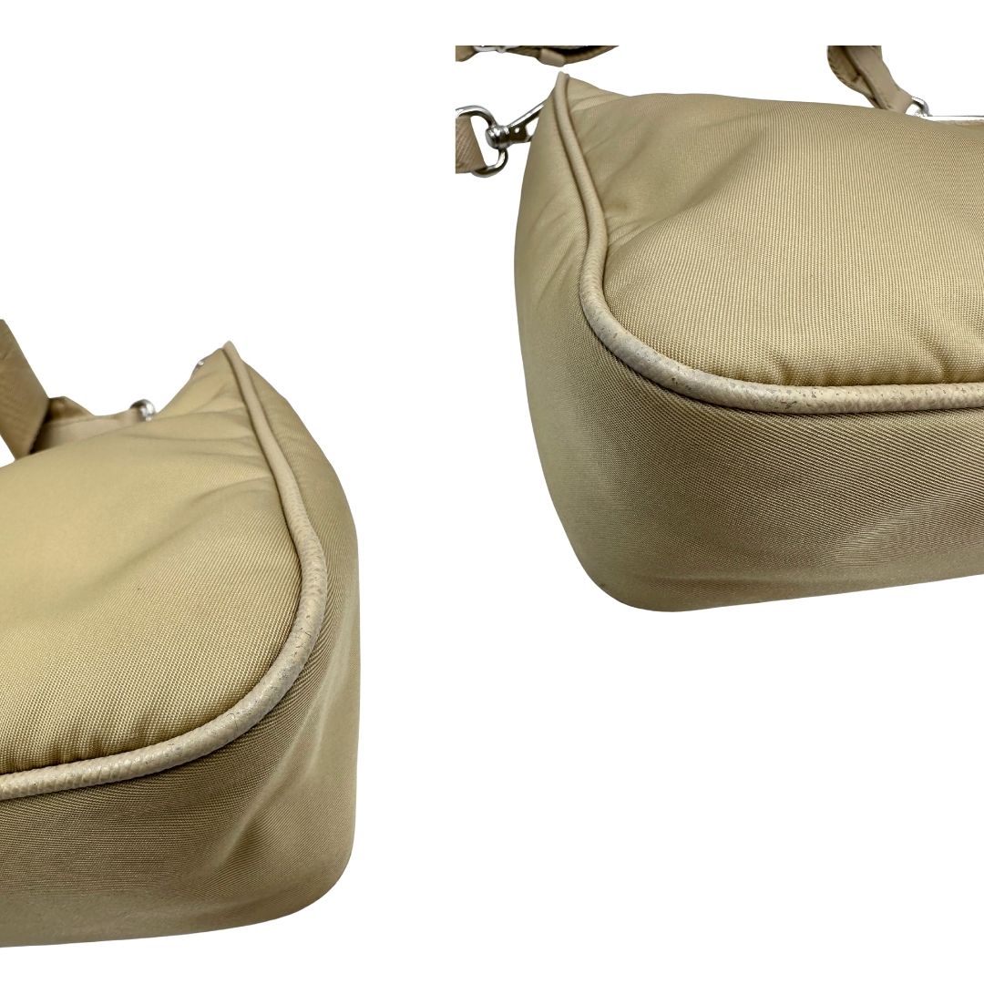 Angoli di una Borsa Prada in Re-Nylon beige con finiture in pelle saffiano tono su tono, munita di un manico in catena e una tracolla in tessuto regolabile e amovibile, impreziosita da pouch rimovibile. Rifinita con parti metalliche argentate e iconico triangolo logato sul front. Indossabile a spalla oppure a tracolla. Originale, usata, di lusso, in ottime condizioni