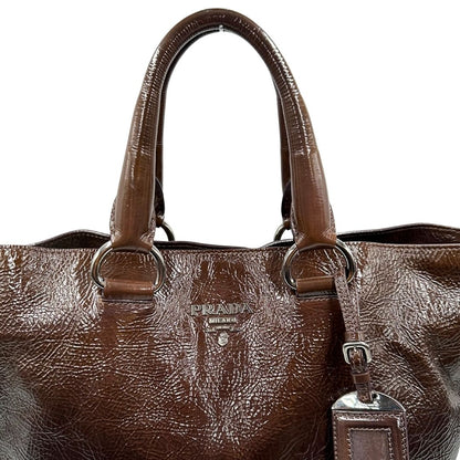 manici Borsa Prada in pelle lucida color cioccolato con parti metalliche argentate; munita di un accessorio porta address e doppi manici. Completa di dustbag, di lusso, originale, ottime condizioni. 