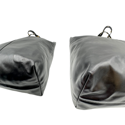 Angoli di una Shopper Versace in pelle nera con parti metalliche dorate munita di due manici con borchie dorate decorative. Indossabile a spalla. N.B. Pochette mancante e punto di aggancio in pelle tagliato dalla precedente cliente. Originale, usata, di lusso, in ottime condizioni.