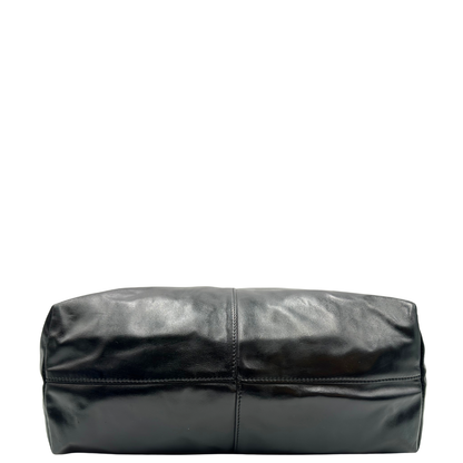 Base di una Shopper Versace in pelle nera con parti metalliche dorate munita di due manici con borchie dorate decorative. Indossabile a spalla. N.B. Pochette mancante e punto di aggancio in pelle tagliato dalla precedente cliente. Originale, usata, di lusso, in ottime condizioni.