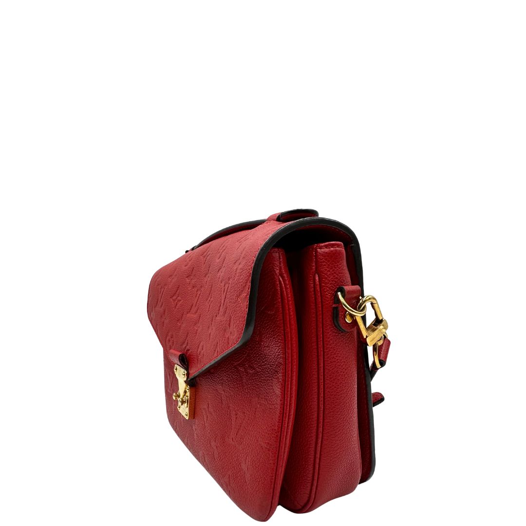 lato Borsa Louis Vuitton Métis in pelle martellata rossa con trama monogram e parti metalliche dorate. Munita di un manico singolo e una tracolla regolabile e amovibile. Completa di corredo, di lusso, originale, ottime condizioni, usata. 