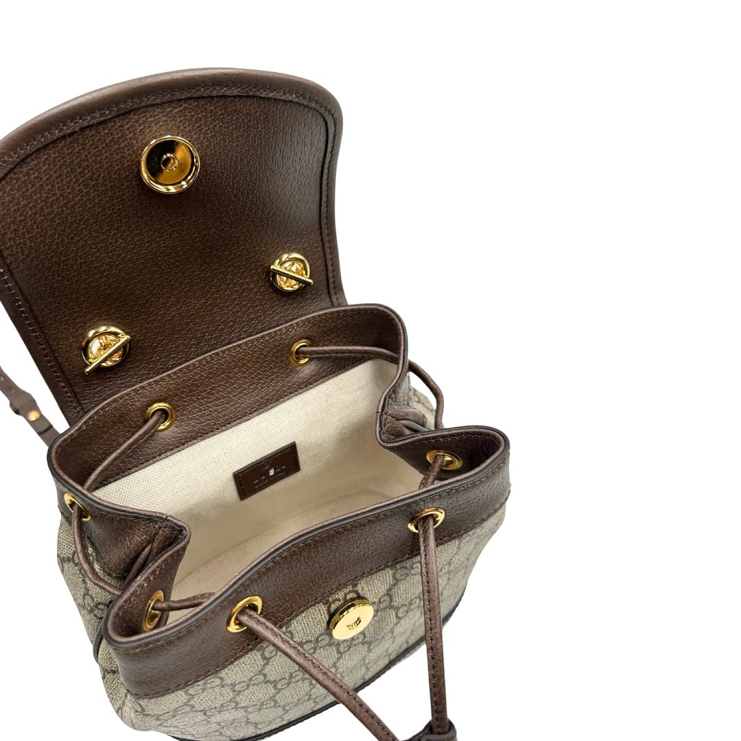 Interno di uno zaino Gucci in canvas beige GG con finiture in pelle marroni e parti metalliche dorate. Iconica striscia Web in verde/rosso sulla patta, impreziosita da un manico in catena amovibile e cinghie in pelle regolabili. Completo di dustbag.