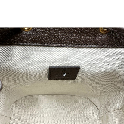 Interno di uno zaino Gucci in canvas beige GG con finiture in pelle marroni e parti metalliche dorate. Iconica striscia Web in verde/rosso sulla patta, impreziosita da un manico in catena amovibile e cinghie in pelle regolabili. Completo di dustbag.