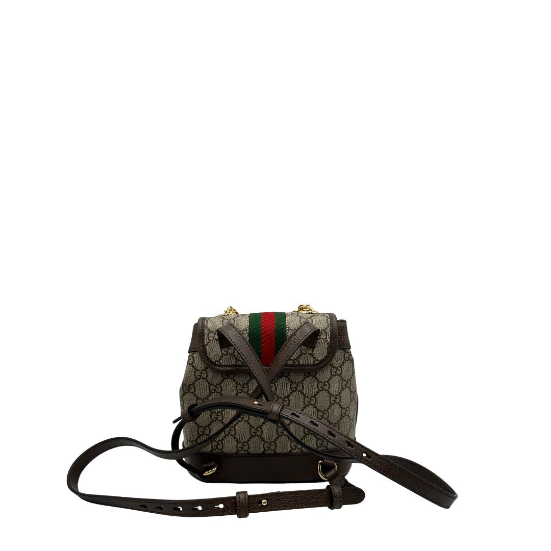 Retro di uno zaino Gucci in canvas beige GG con finiture in pelle marroni e parti metalliche dorate. Iconica striscia Web in verde/rosso sulla patta, impreziosita da un manico in catena amovibile e cinghie in pelle regolabili. Completo di dustbag.