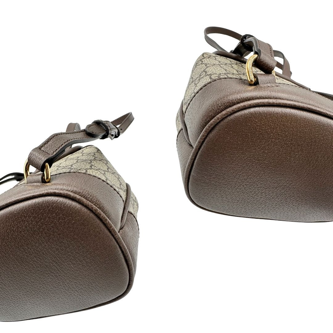 Angoli di uno zaino Gucci in canvas beige GG con finiture in pelle marroni e parti metalliche dorate. Iconica striscia Web in verde/rosso sulla patta, impreziosita da un manico in catena amovibile e cinghie in pelle regolabili. Completo di dustbag.