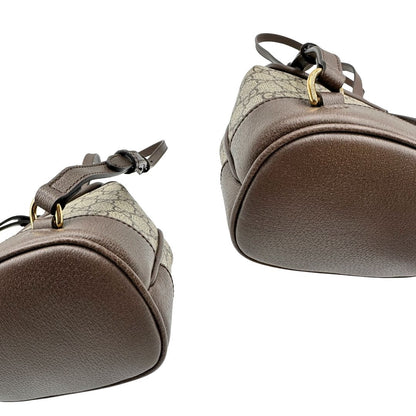 Angoli di uno zaino Gucci in canvas beige GG con finiture in pelle marroni e parti metalliche dorate. Iconica striscia Web in verde/rosso sulla patta, impreziosita da un manico in catena amovibile e cinghie in pelle regolabili. Completo di dustbag.