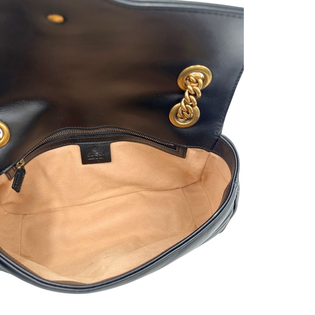 Interno di una Borsa Gucci Marmont in pelle matelassé nera con tracolla scorrevole in catena e spallaccio in pelle, rifinita con parti metalliche dorate; indossabile a spalla oppure a tracolla. Completa di dustbag. Originale, usata, di lusso, in ottime condizioni.