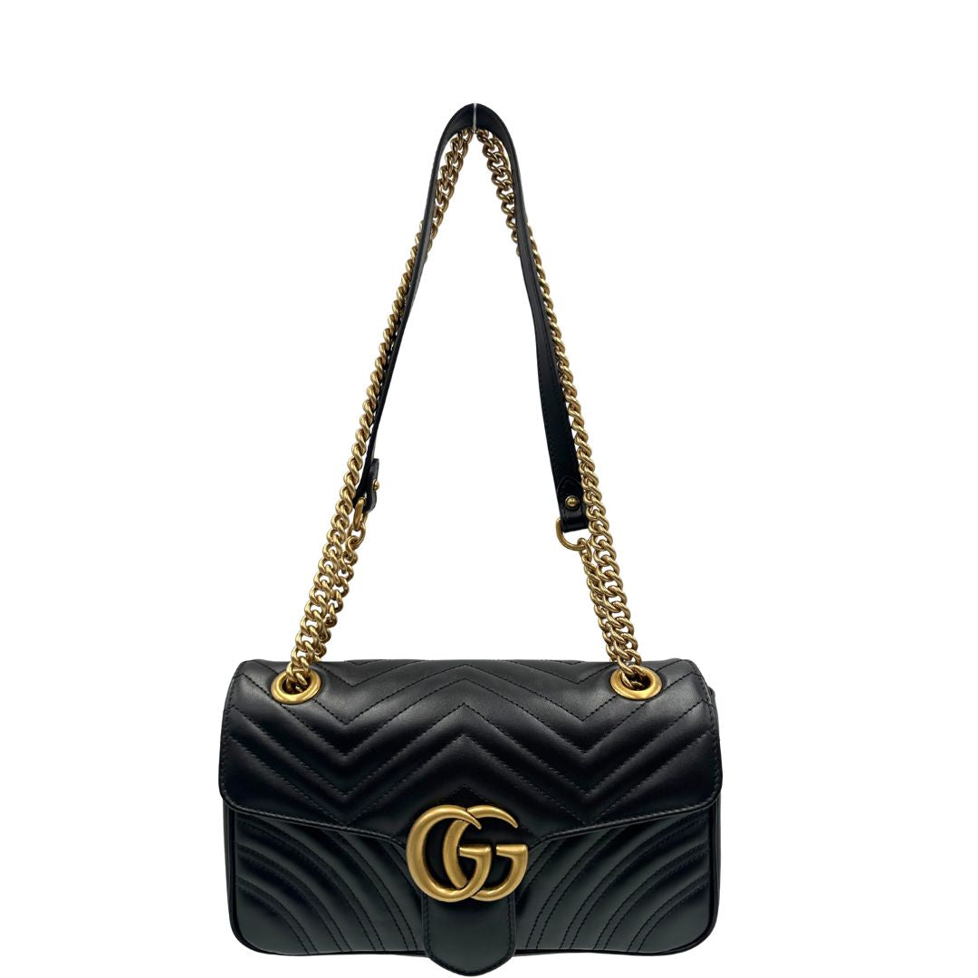 Front di una Borsa Gucci Marmont in pelle matelassé nera con tracolla scorrevole in catena e spallaccio in pelle, rifinita con parti metalliche dorate; indossabile a spalla oppure a tracolla. Completa di dustbag. Originale, usata, di lusso, in ottime condizioni.