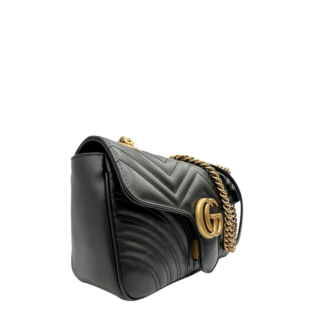 Lato destro di una Borsa Gucci Marmont in pelle matelassé nera con tracolla scorrevole in catena e spallaccio in pelle, rifinita con parti metalliche dorate; indossabile a spalla oppure a tracolla. Completa di dustbag. Originale, usata, di lusso, in ottime condizioni.