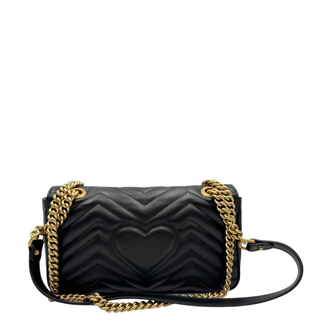 Retro di una Borsa Gucci Marmont in pelle matelassé nera con tracolla scorrevole in catena e spallaccio in pelle, rifinita con parti metalliche dorate; indossabile a spalla oppure a tracolla. Completa di dustbag. Originale, usata, di lusso, in ottime condizioni.