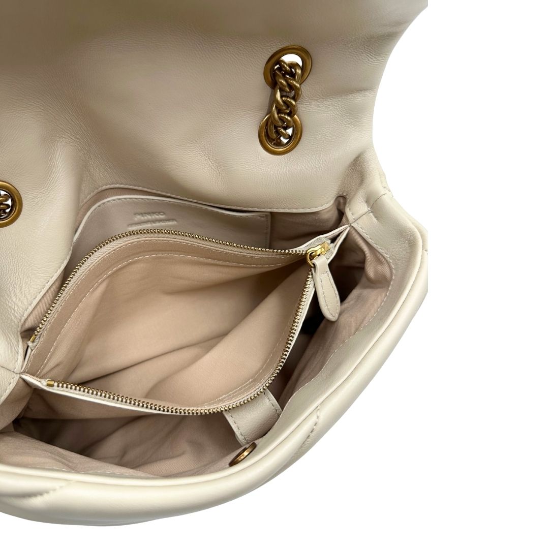 Interno di una borsa Pinko in pelle trapuntata bianco latte con parti metalliche dorate; munita di una tracolla in catena scorrevole con spallaccio in pelle. Completa di dustbag e cartellino. Indossabile a spalla o a tracolla.