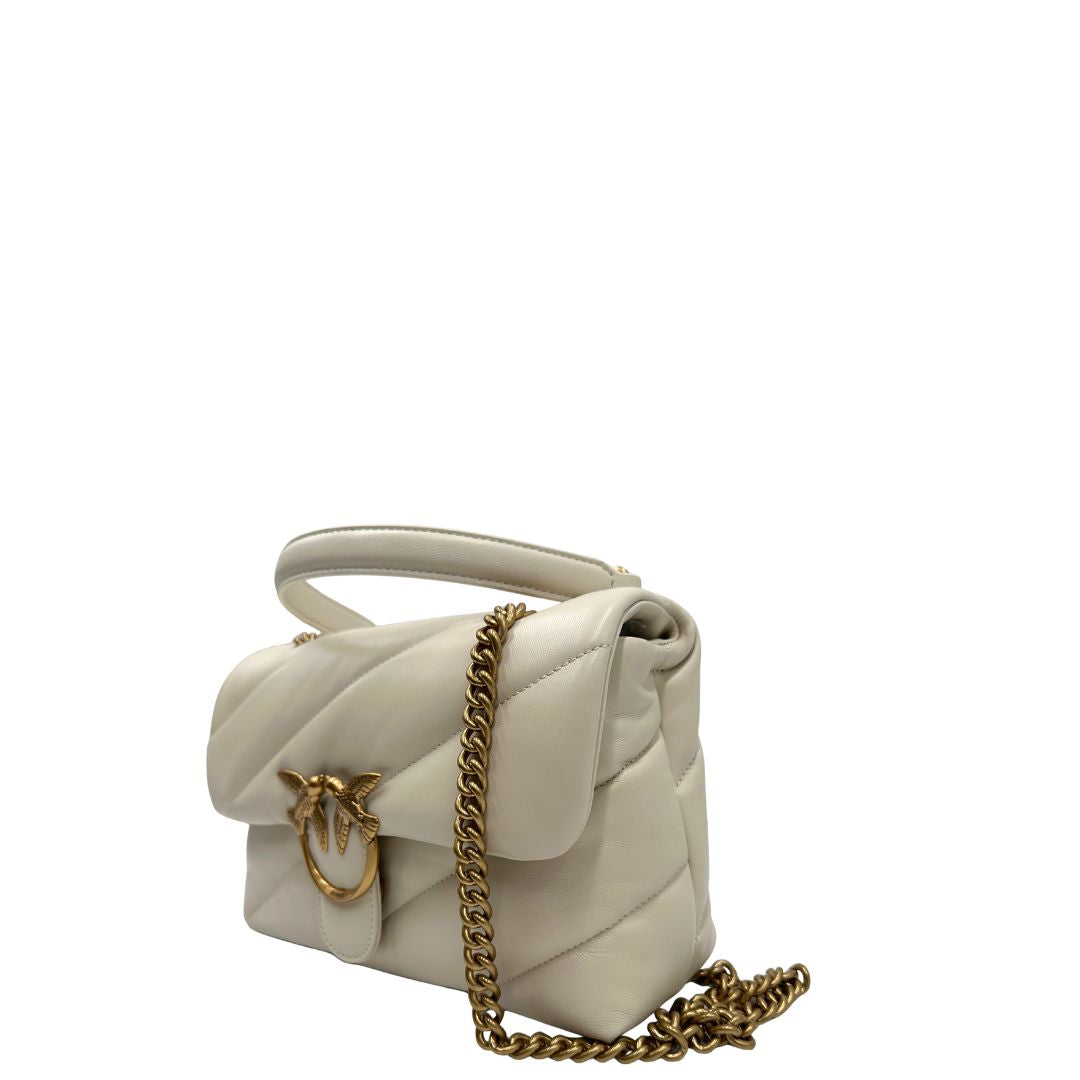 Laterale destro di una borsa Pinko in pelle trapuntata bianco latte con parti metalliche dorate; munita di una tracolla in catena scorrevole con spallaccio in pelle. Completa di dustbag e cartellino. Indossabile a spalla o a tracolla.