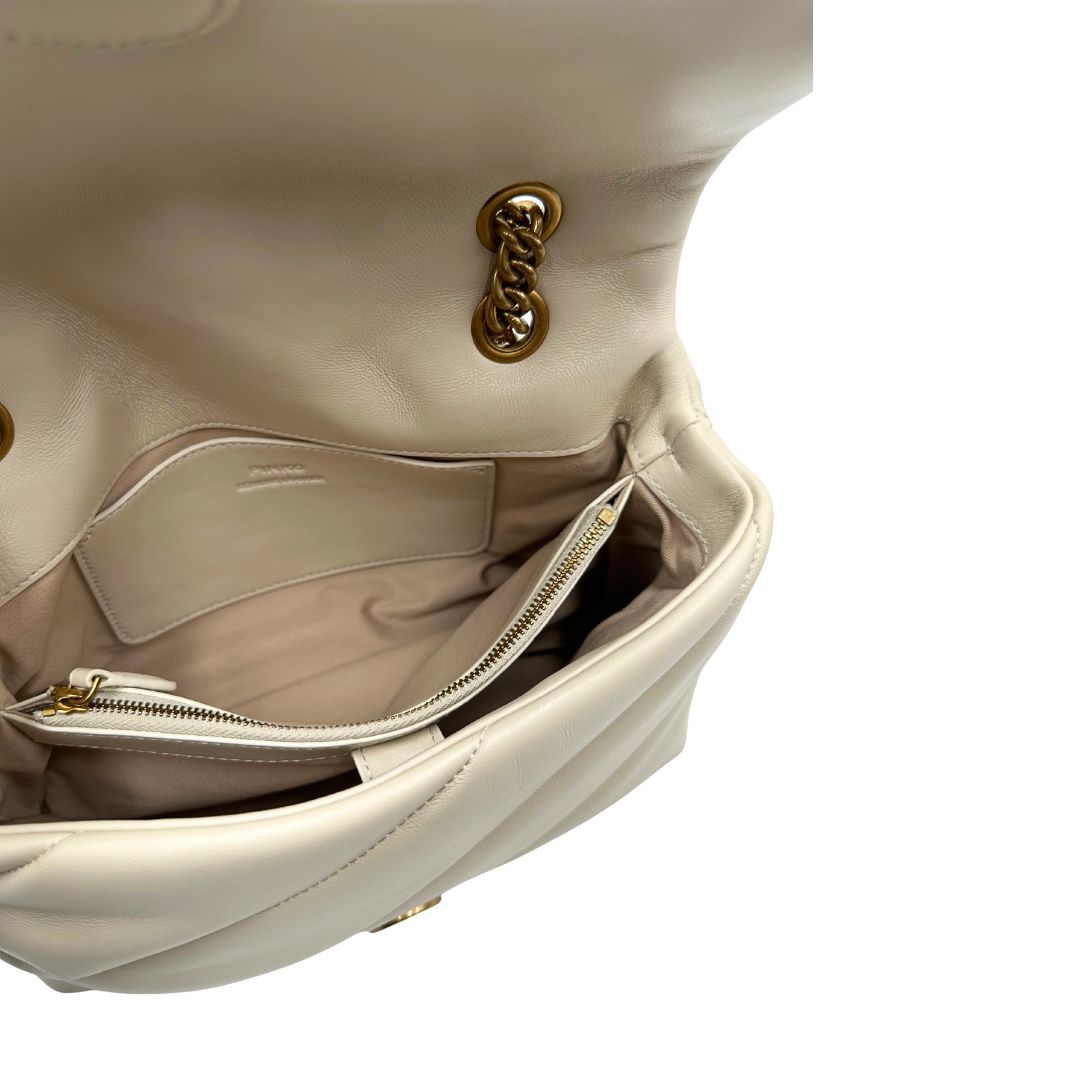 Interno di una borsa Pinko in pelle trapuntata bianco latte con parti metalliche dorate; munita di una tracolla in catena scorrevole con spallaccio in pelle. Completa di dustbag e cartellino. Indossabile a spalla o a tracolla.