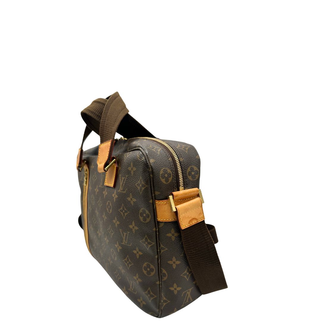 Lato sinistro di una Borsa Louis Vuitton in canvas marrone monogram con finiture in vacchetta naturale e parti metalliche dorate; munita di due manici e una tracolla in tessuto regolabile. Completa di dustbag. Originale, usata, di lusso, in ottime condizioni.
